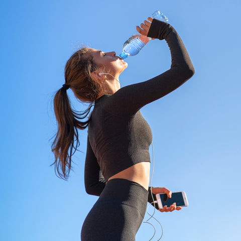 water woman drinking water to rehydrate and athletics