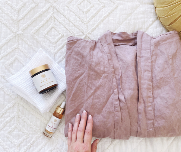 Robe and skincare products on bed