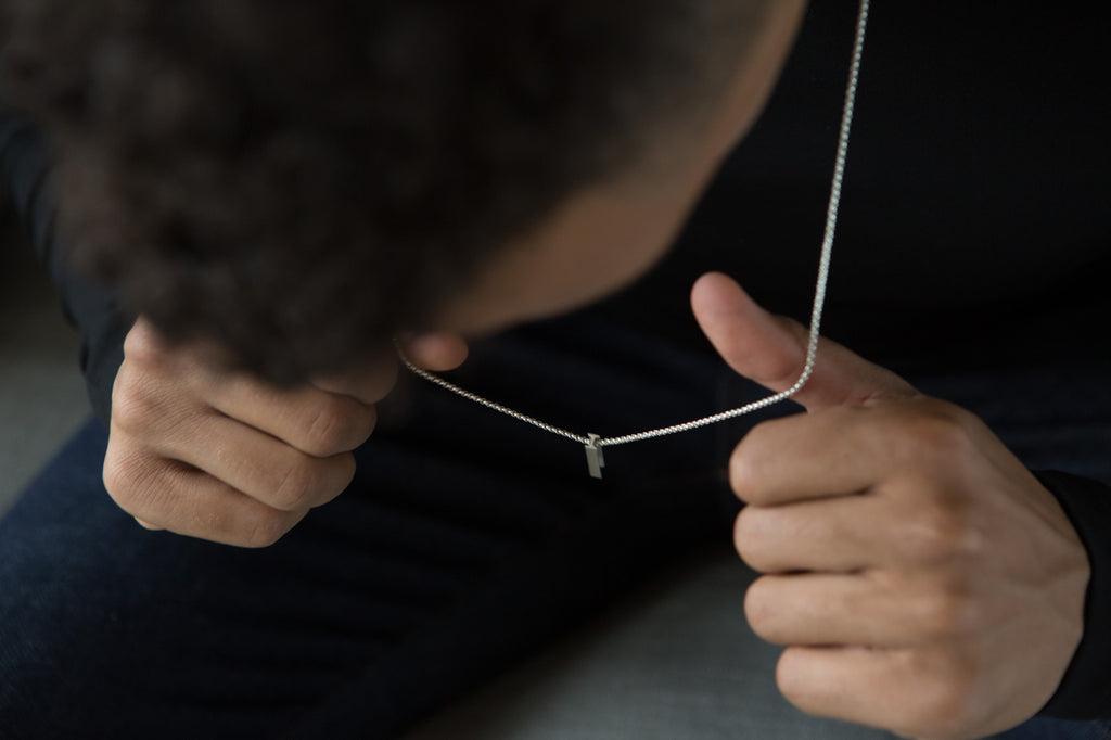 a man wears a necklace inspired by an i-beam