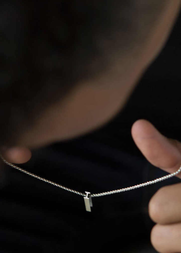 A sterling silver letter 'I' pendant necklace on a man