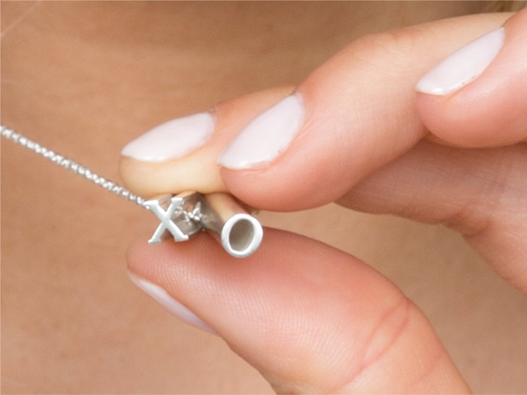 A sterling silver 'XO' pendant necklace being worn by a girl.