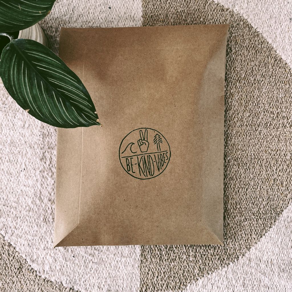 Image features Be Kind Vibes sustainable packaging kraft mailer with a Be Kind Vibes stamped logo on the top