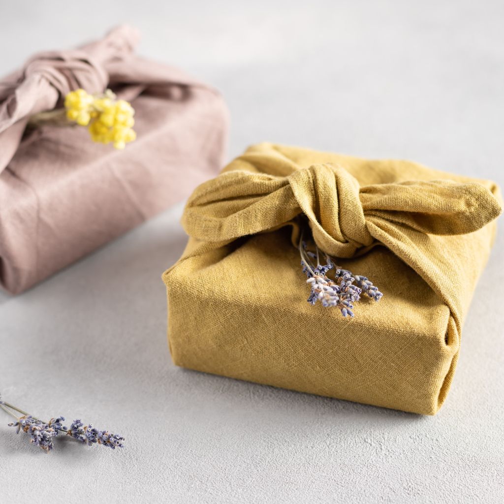 Image features two holiday gifts wrapped with sustainable gift wrapping and a sprig of lavender. 