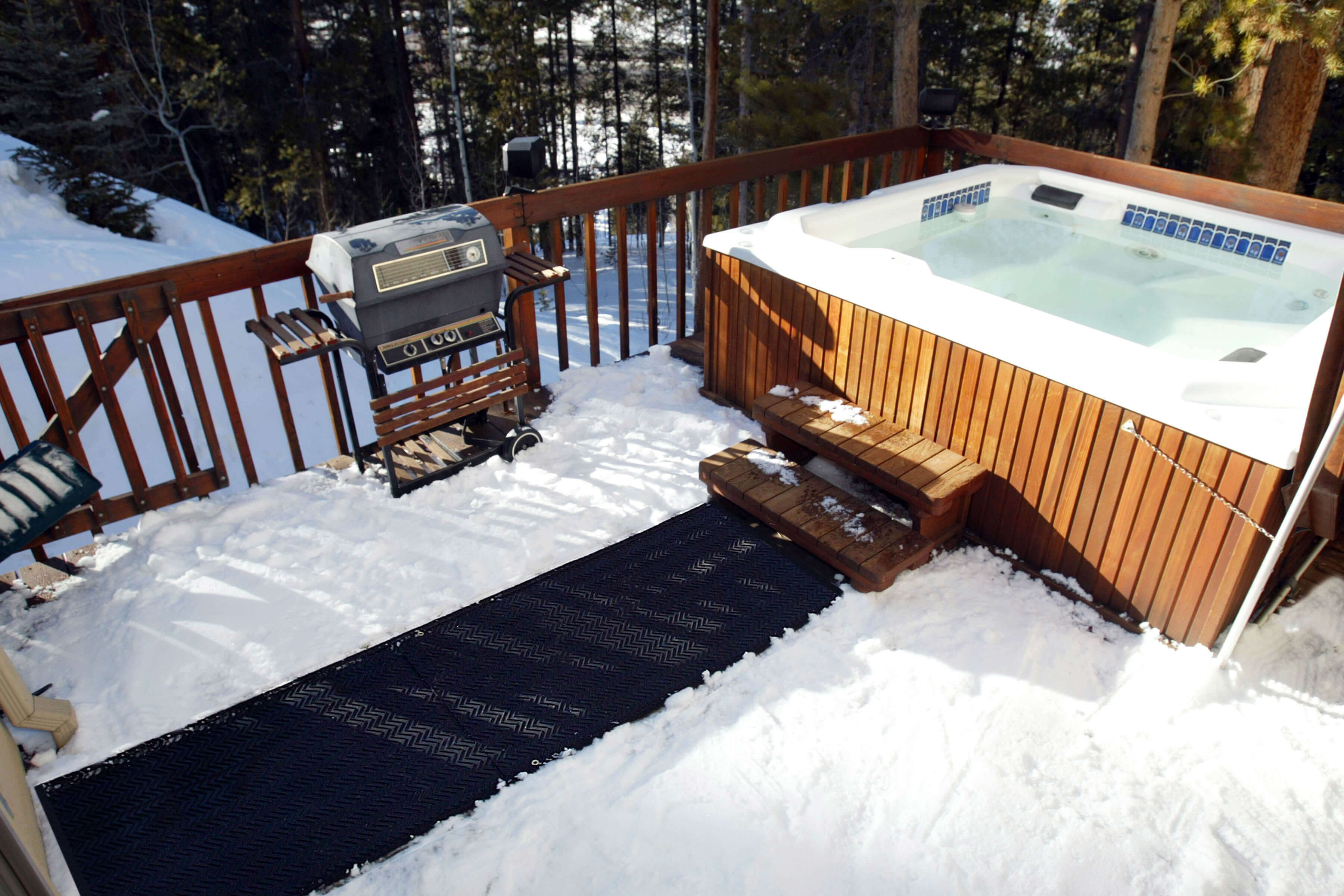 HeatTrak mat walkway on snow-covered deck, leading to steaming hot tub