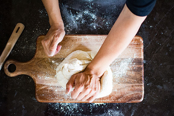 hands kneading dough preparing for pizza oven outdoors