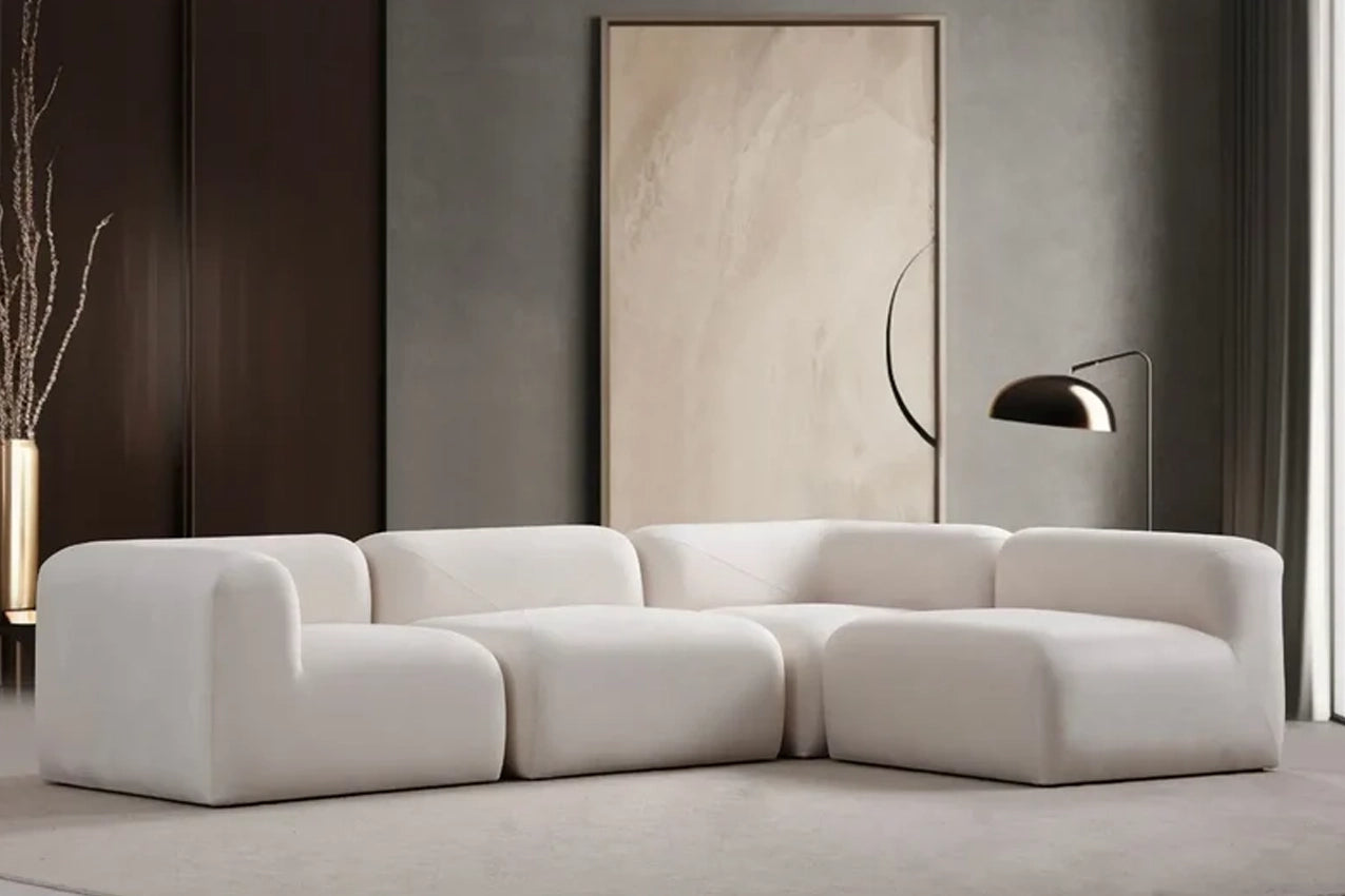 Canapé modulable contemporain en tissu blanc, au design arrondi et minimaliste, dans un salon haut de gamme avec miroir décoratif et lampe arc en métal doré.