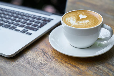 LATTE SITTING ON A TABLE BY A LAPTOP