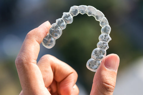 Someone holding clear aligners in their hands.