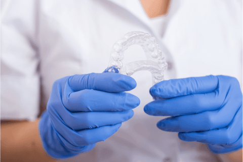 blue gloves orthodontist holding clear plastic retainers