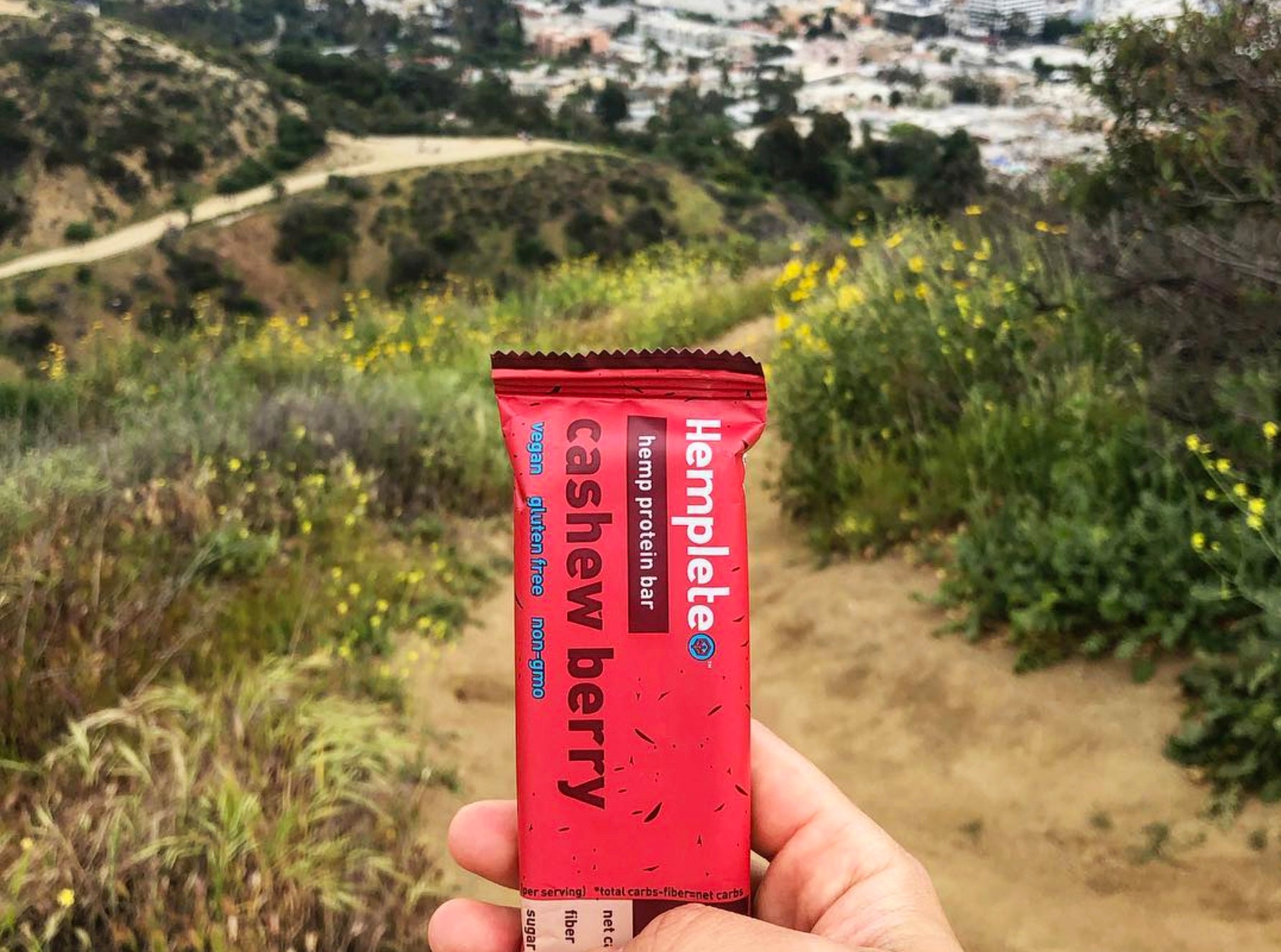 A hemp protein bar held up in front of trails