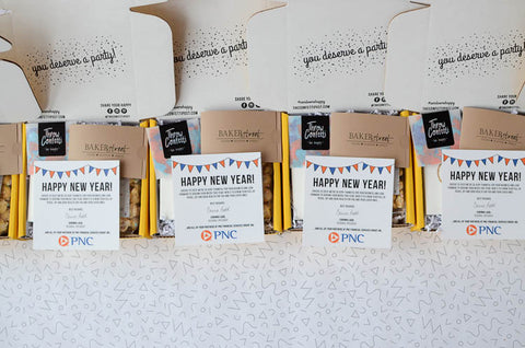 Lined up open gift boxes on a white and black background, filled with custom greeting card with logo, confetti and gift cards: Best Ideas For Remote Employee Gifts New Year Gift Boxes