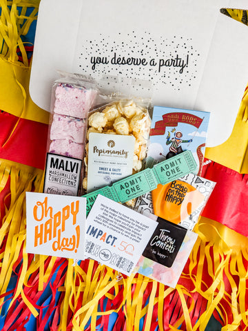 Canrnival themed custom gift box filled with pink marshmallows, popcorn, playing cards, confetti, balloon and gift message with company logo: Custom Corporate Gift Box Idea for Virtual Employees