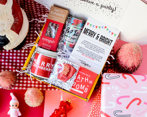 Holiday Christmas Gift Box for Employees: Red gifts and background, gift box with Merry Everything Candle, Red Bath Bomb, and chocolate pretzels