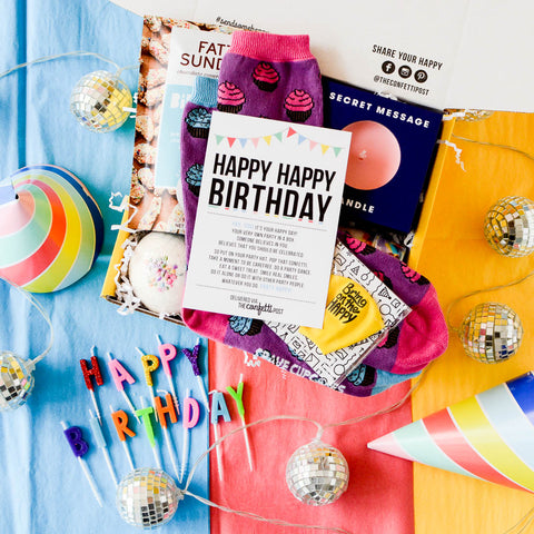 Birthday Gift Box filled with card, candle, treats, balloon and socks on colorful backround with birthday hat and candles that say Happy Birthday