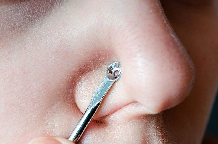 person using a blackhead removal tool on their nose