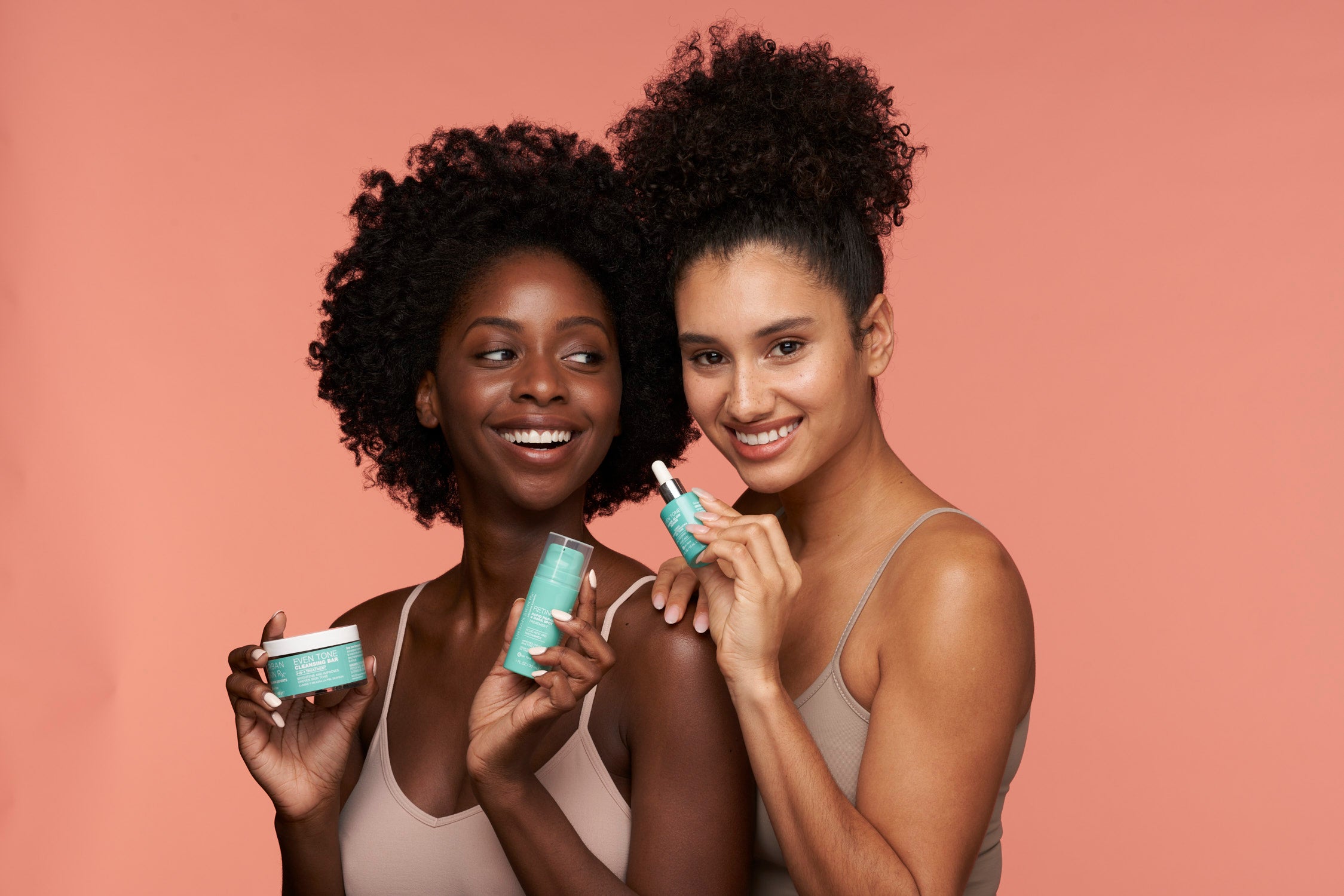 Two diverse woman of melanated complexions holding Urban Skin Rx® products while smiling