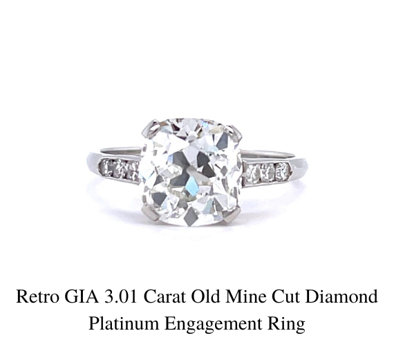 复古 GIA Old Mine 3.01 克拉老矿式切割钻石订婚戒指的特写，采用铂金镶嵌，白色背景。戒环两侧有一颗中间的大钻石，周围环绕着三颗较小的钻石。