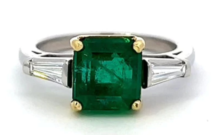 GIA Zambian emerald with 2 baguette cut diamonds on the side on a platinum setting with gold prongs 