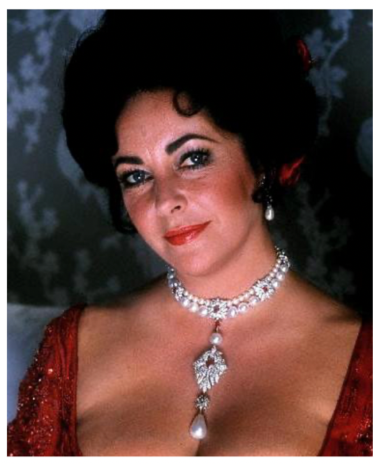 Color photograph of Liz Taylor in a radiant red dress, elegantly wearing the Peregrina pearl necklace, highlighting its lustrous beauty against the backdrop of her decolletage.