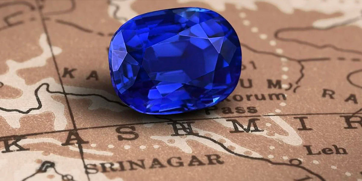 Closeup of a blue sapphire gemstone sitting on a brown map of Kashmir