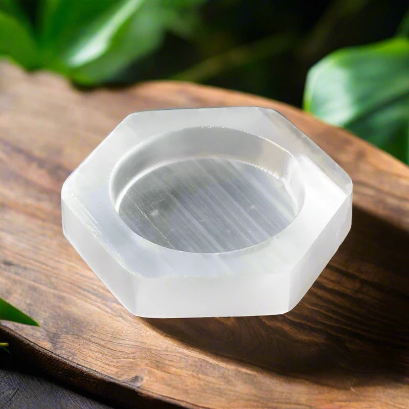 Natural hexagon selenite bowl with soft white glow, placed on a wooden surface – used for spiritual cleansing and crystal charging.