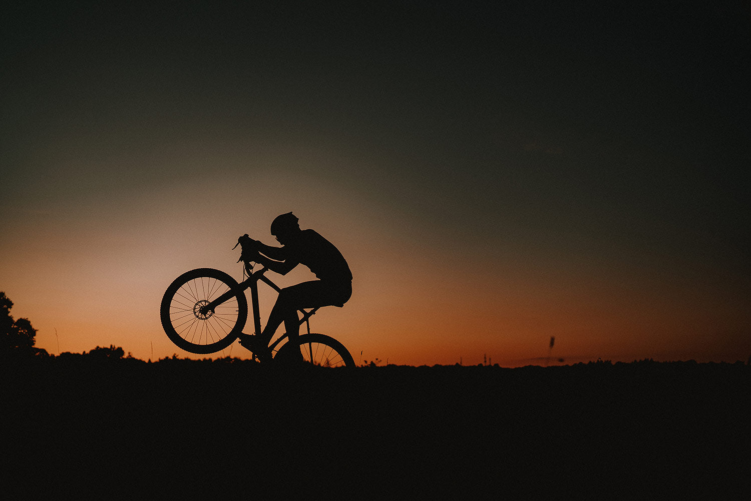 Cyclist in Silhouette doing a wheely