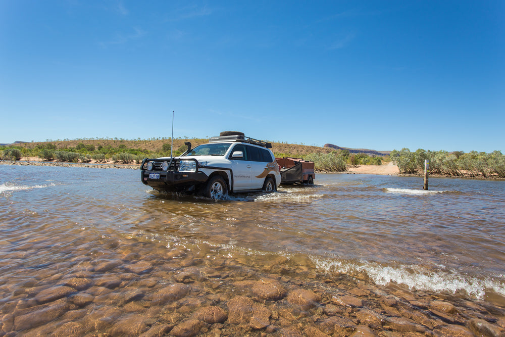 4WD and camper trailer driving across water