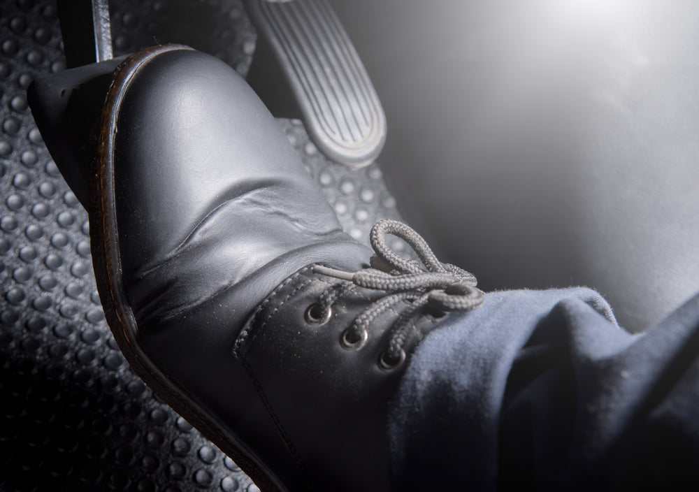 Black laced boot pressing down on a brake pedal