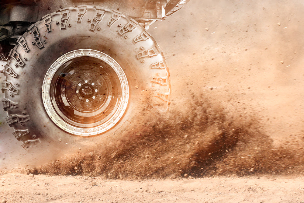 Close up of a 4WD tyre kicking up dust
