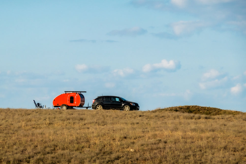 Car towing a camper trailer off-road grassy terrain