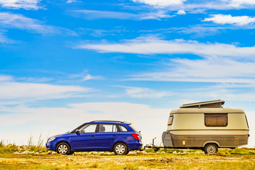 Blue hatchback towing an old-style camper trailer