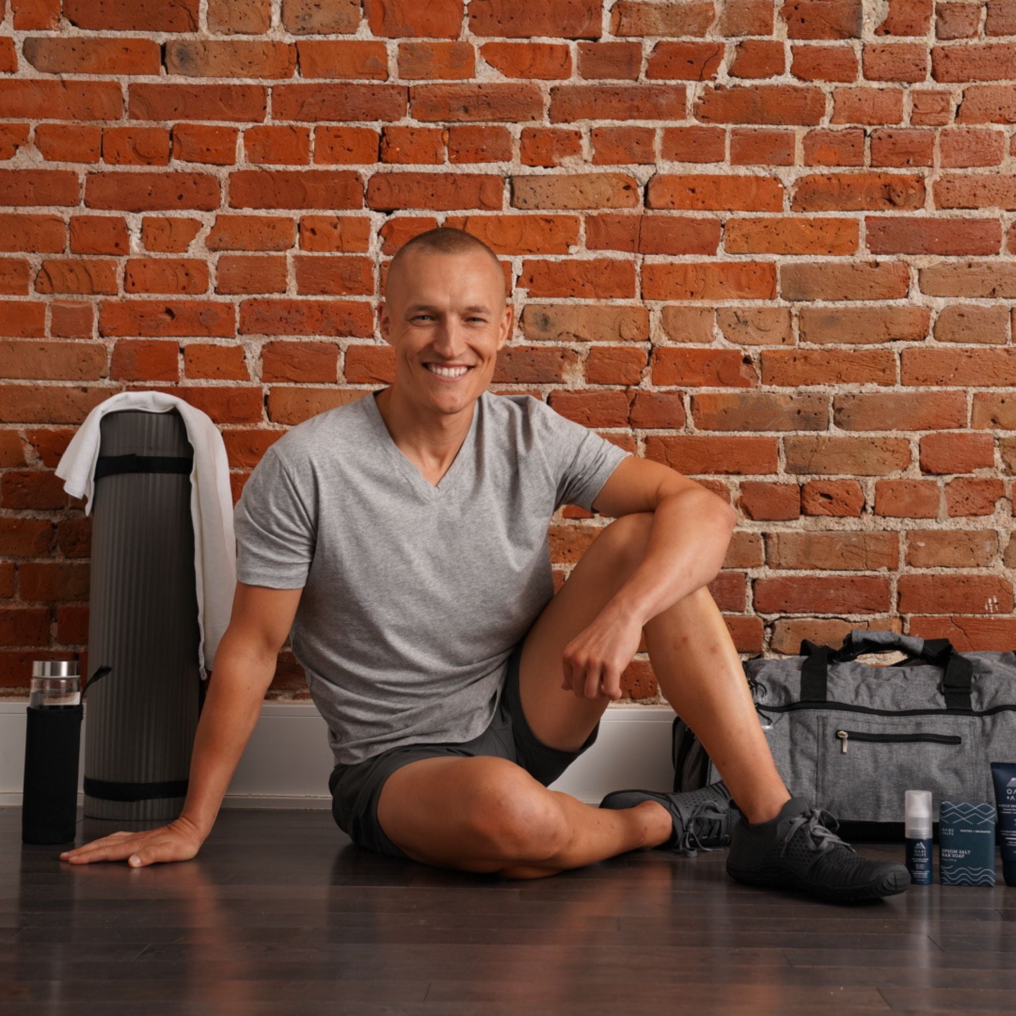 Matt Wilpers sitting on yoga mat with Oars + Alps Athlete Line collection around him