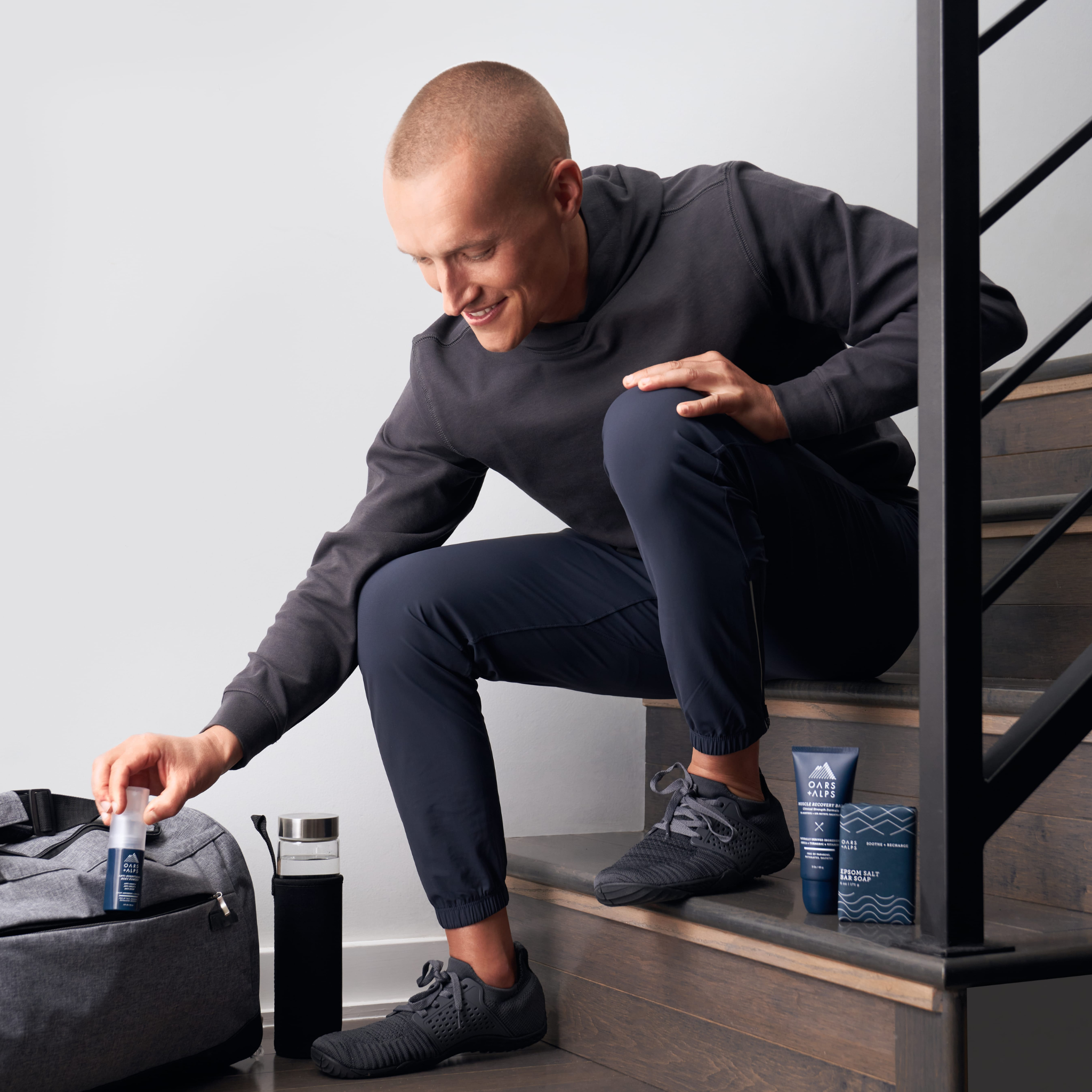 Matt Wilpers sitting on stairs putting Oars + Alps Anti-Everything Powder in his gym bag