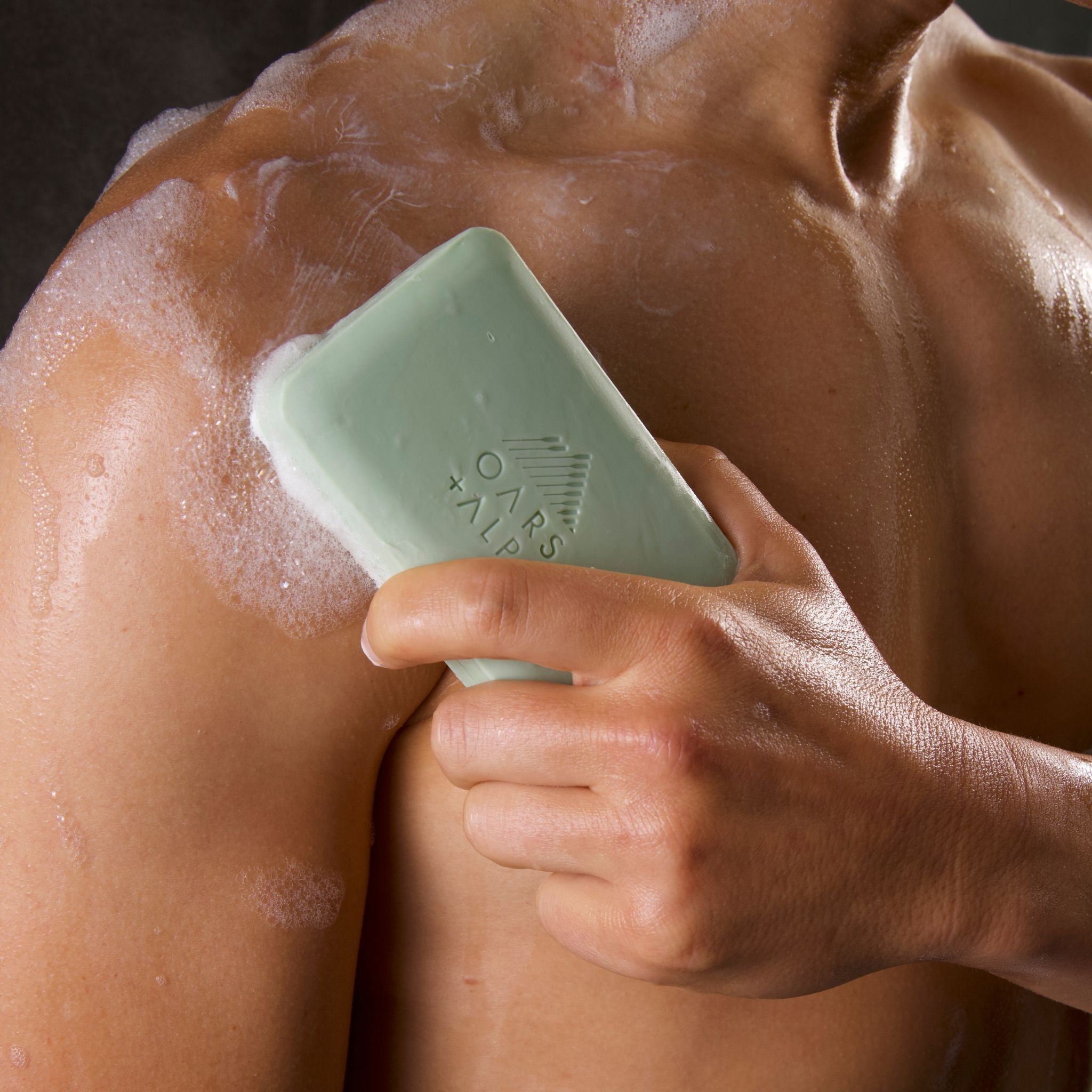 Man in shower applying Epsom Salt Bar Soap to chest
