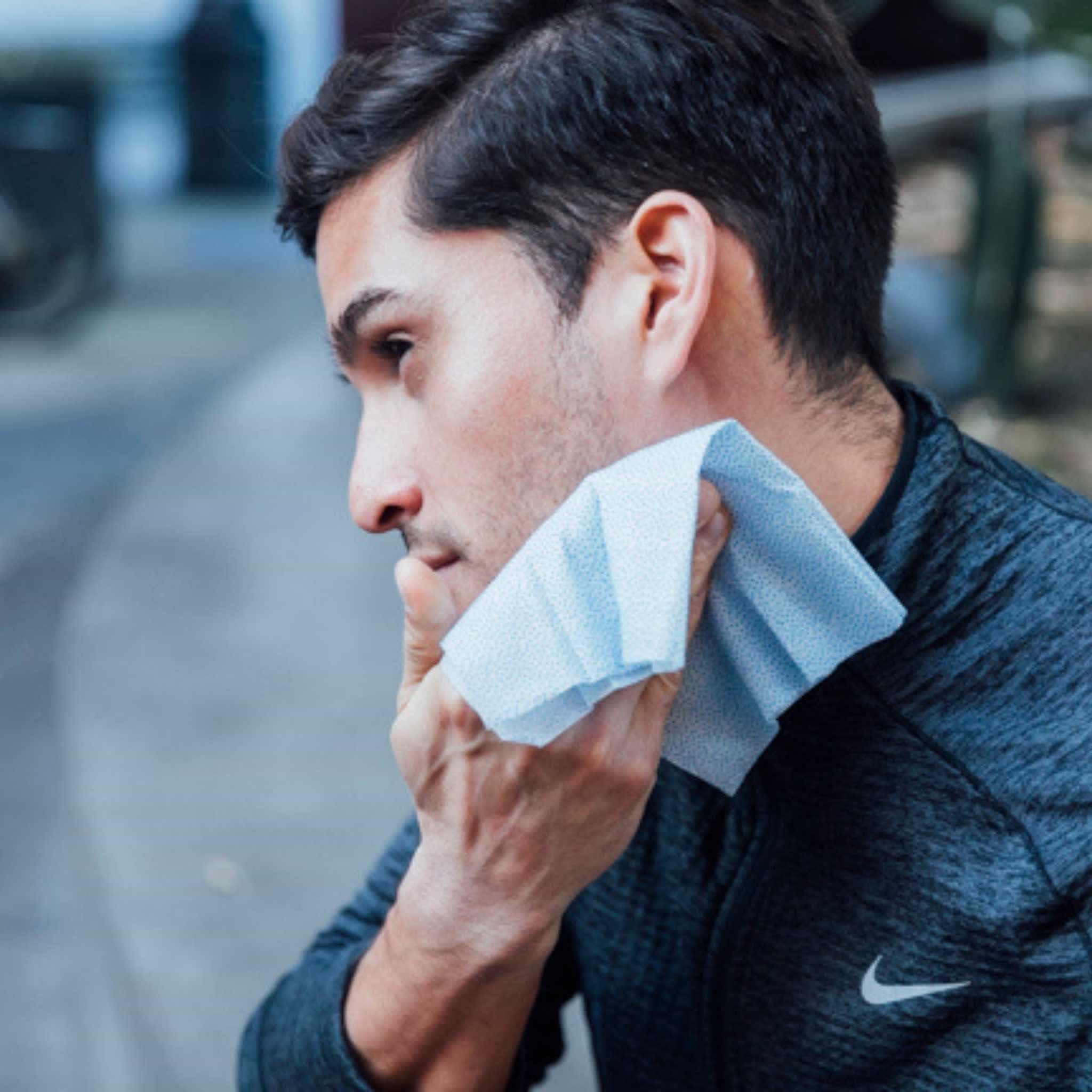 Man cooling down skin post-workout with a body wipe made with caffeine
