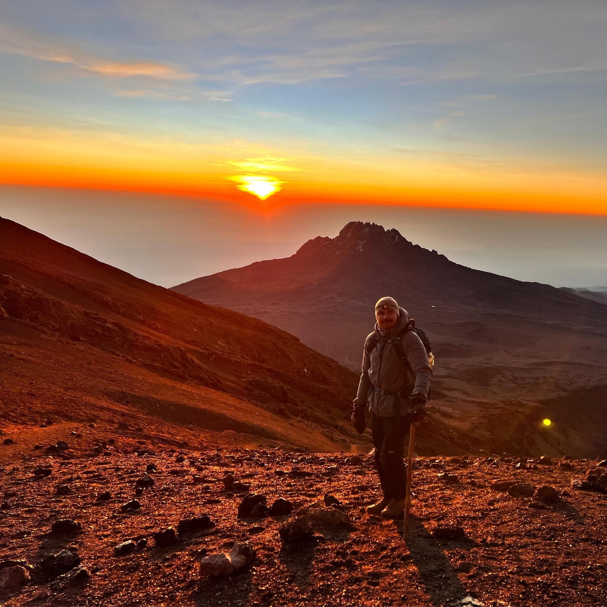 Man at sunrise on top of Mt. Kilimanjaro