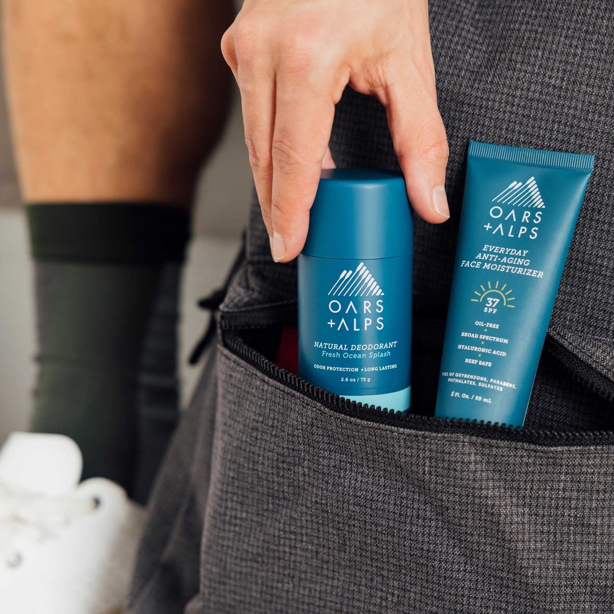 Man putting Oars + Alps Aluminum-Free Deodorant into backpack