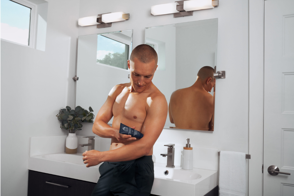 Matt Wilpers rubbing Oars + Alps' Muscle Recovery Balm onto his arm in the bathroom
