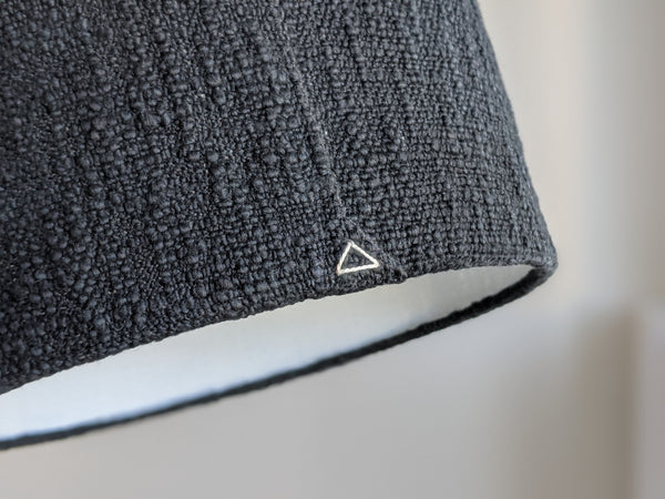 close up of cream triangle stitch detail on back of black boucle lamp shade