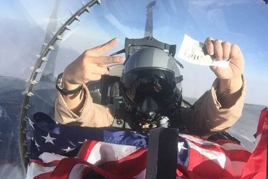 Pilot holding EPIC bar and American flag in cockpit