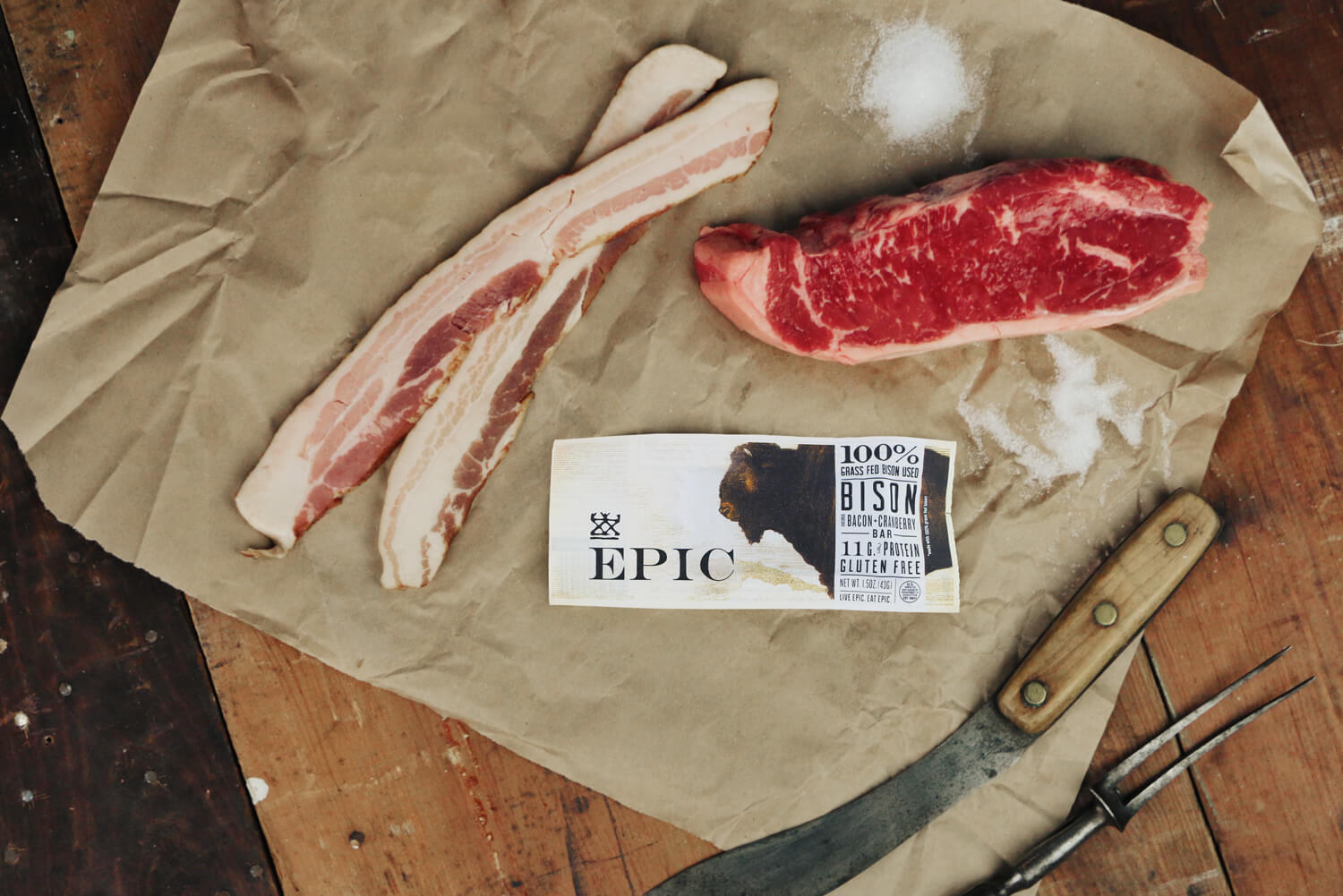 EPIC Bison bar along with raw bacon and bison all laid out on parchment paper 