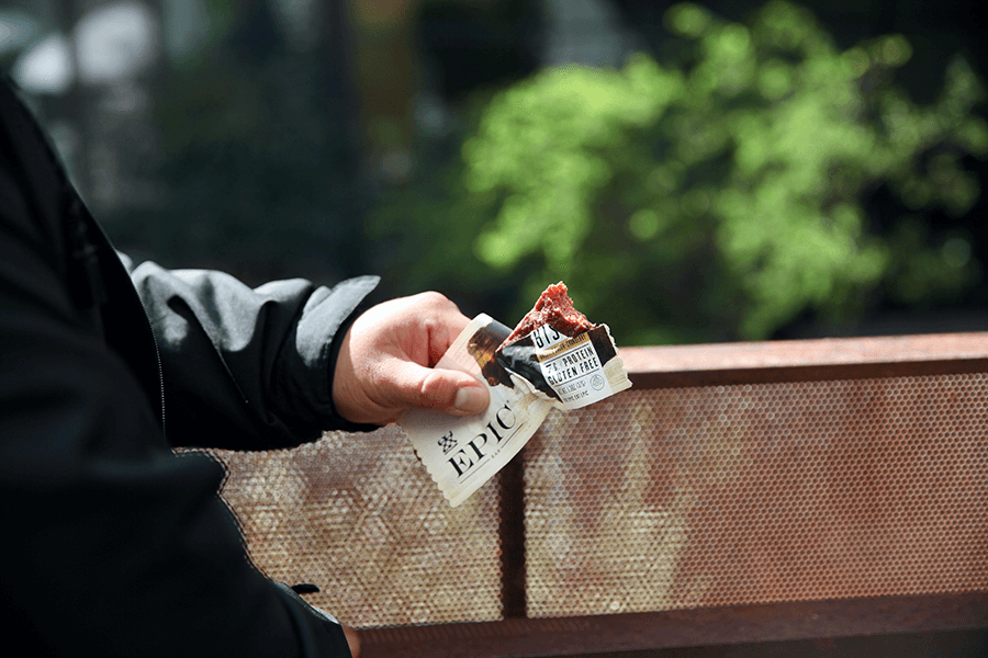 Image of a man holding a open EPIC bison bacon cranberry bar.