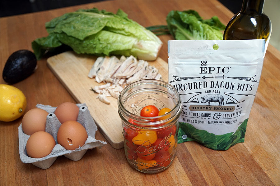 Items to make a Summer Cobb Salad. Head of romaine lettuce, cherry tomatoes, olive oil, lemon, avocado, four eggs, grilled chicken and a bag of EPIC Hickory Smoked Bacon Bits.