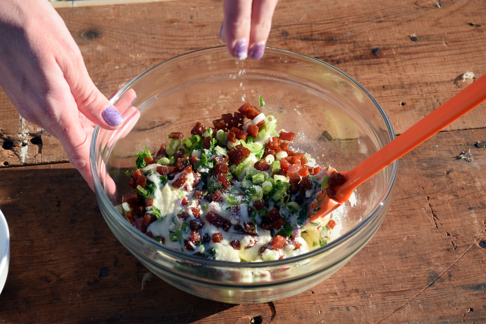 the ingredients of the epic blt dip being mixed in a serving bowl