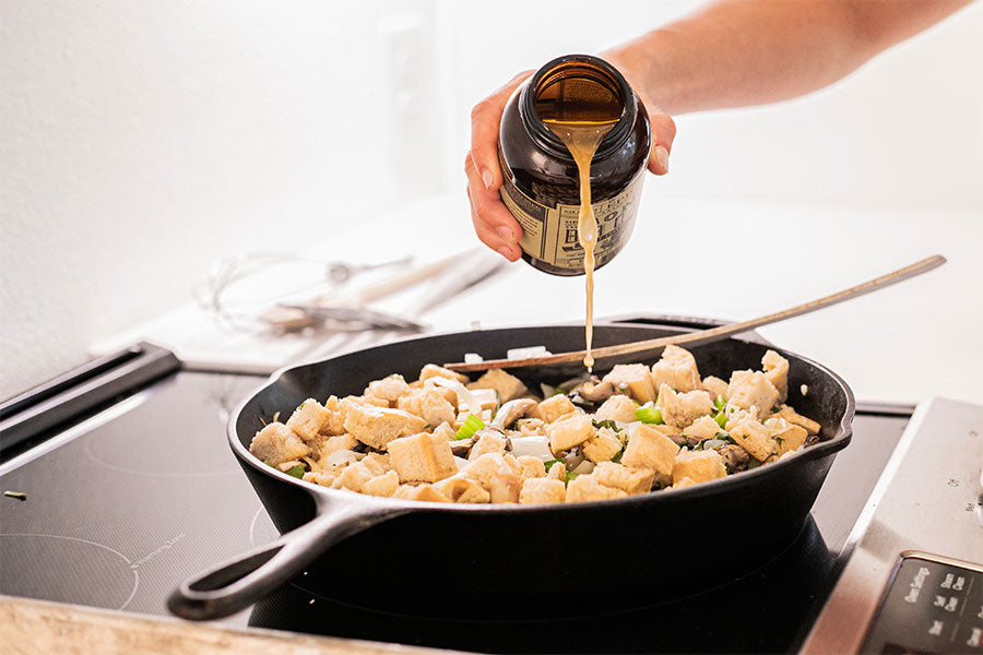 Epic Turkey Bone Broth being poured in to the stove top pan containing the chopped ingredients of EPIC's Bone Broth Dressing recipe.