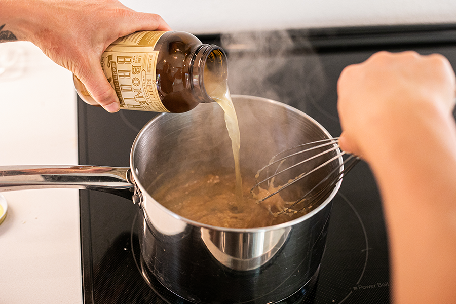 Epic's Chicken Bone Broth being poured into a stove top pan to make the Chicken Fat Gravy.