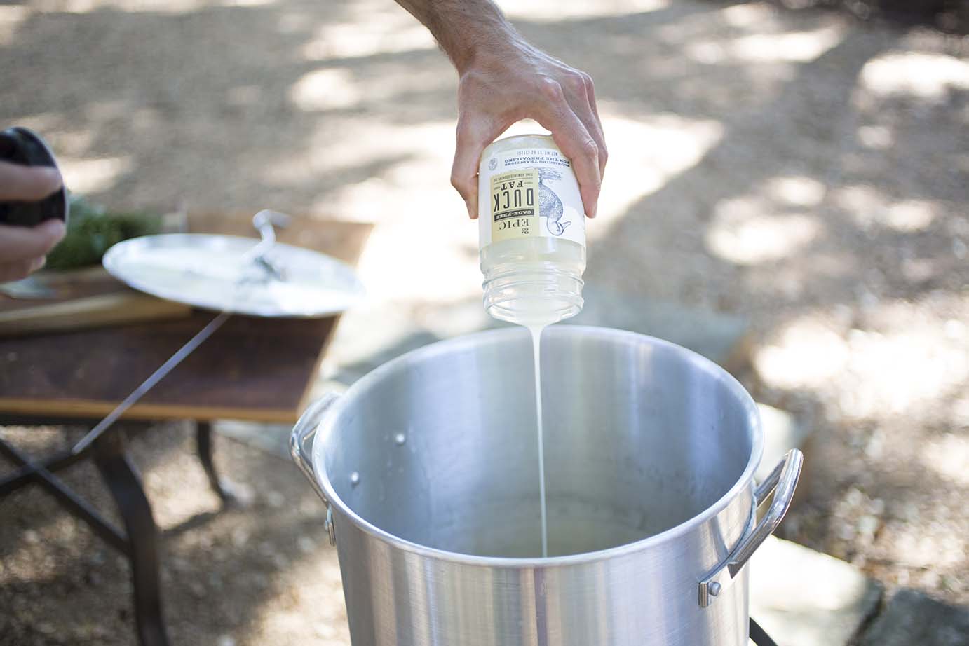 A hand is shown pouring EPIC duck fat into fryer 