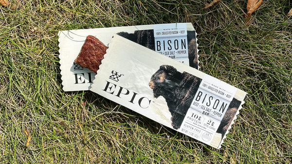 Two of EPIC's Bison with Beef Sea Salt Pepper Bars on top of each other laying on grass.