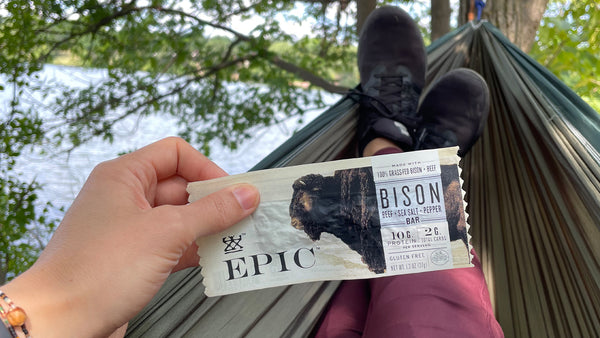 A person kicked back in a hammock, holding a EPIC Bison with Beef Sea Salt Pepper Bar.