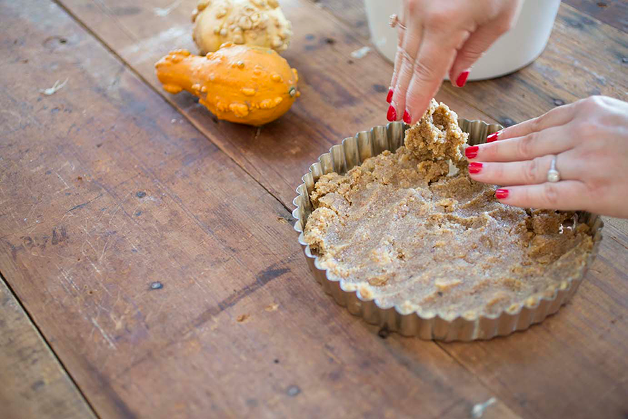 Hands forming the pie crust in a pie dish.